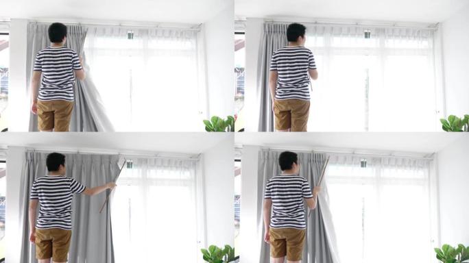 亚洲男孩haning窗帘与窗户在家里，搬家的概念。