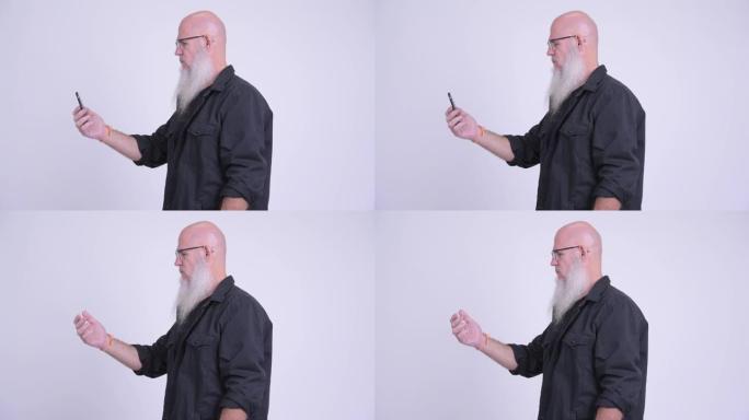 成熟的秃头大胡子男人使用电话的纵断面图