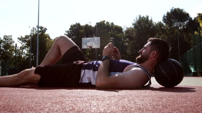 年轻人在手机上联网，躺在篮球场上