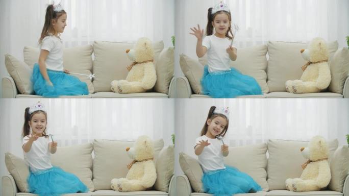 小仙女手里拿着魔杖坐在沙发上，变出她的泰迪熊，然后将魔杖对准相机。