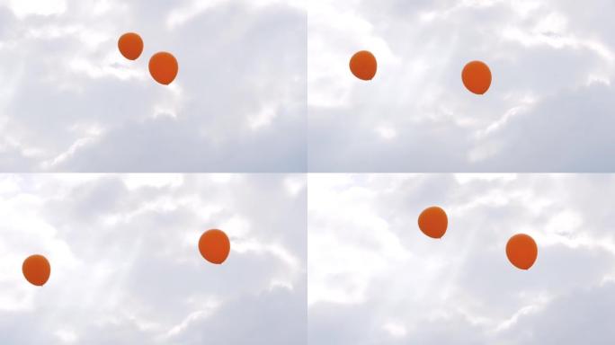 在户外节日上，橙色气球在风中摇曳，在灰色的天空中摇摆