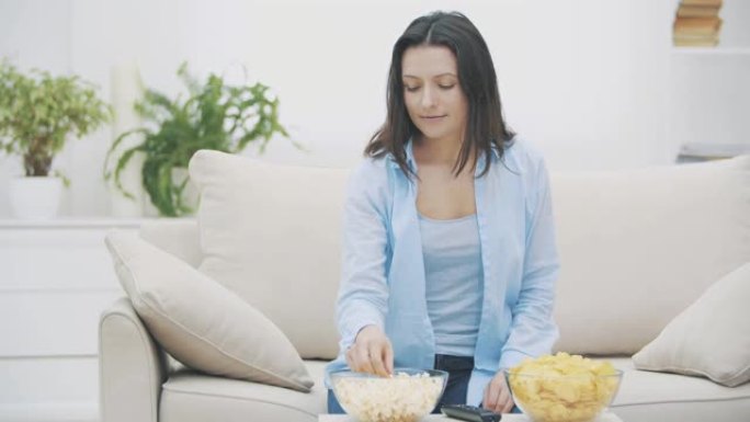 幸福的女人正试图在爆米花和薯条之间做出选择。漂亮女人在嚼爆米花。4K。