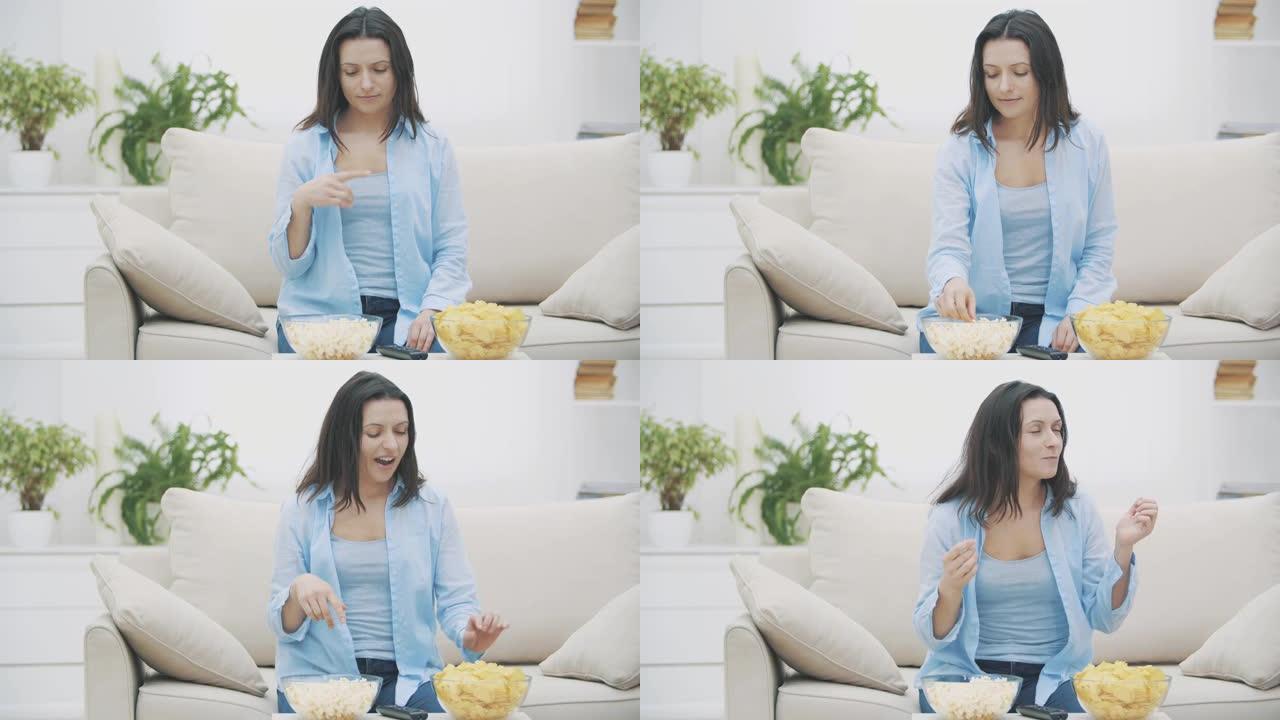 幸福的女人正试图在爆米花和薯条之间做出选择。漂亮女人在嚼爆米花。4K。