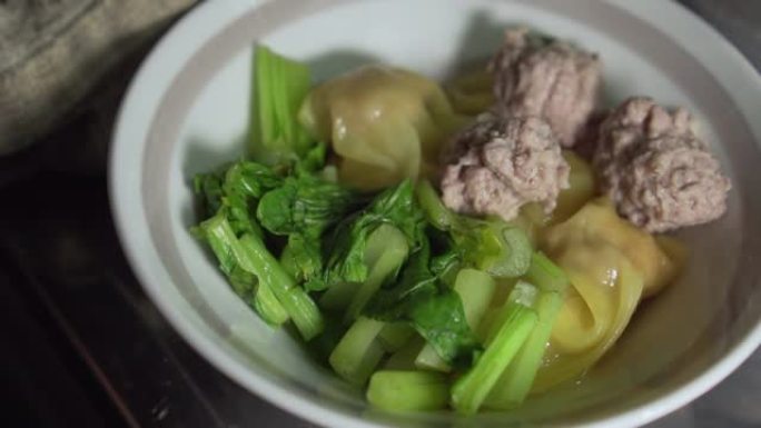 一个装有饺子水的碗，里面有猪肉末，菜和猪肉末。