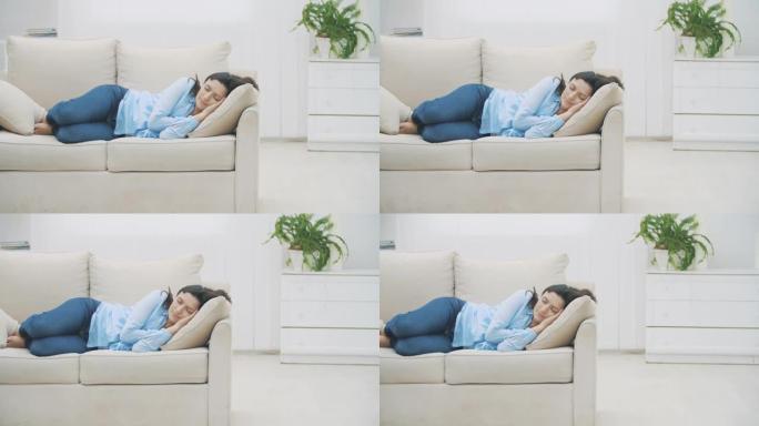 慢速。满意的黑发女人睡在家里的沙发上。女人在做愉快的梦。4K。
