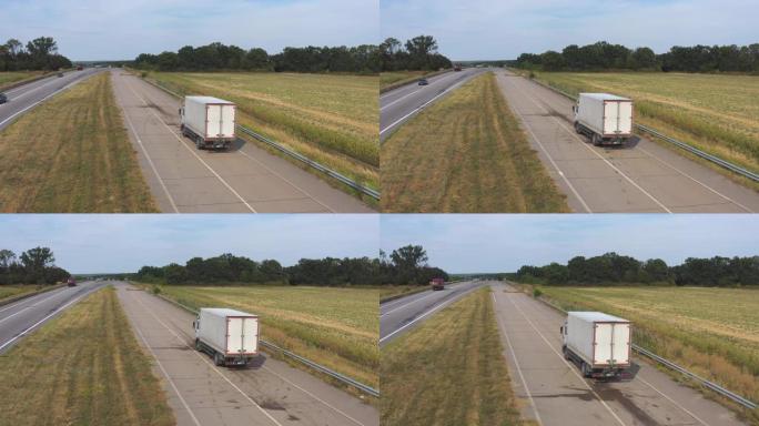 载货拖车在公路上行驶并运输货物的卡车的航拍。飞越送货卡车，沿着高速公路经过乡村，周围风景优美的自然环
