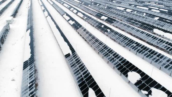 空中: 冬天被雪覆盖的光伏。雪中的太阳能电池板被雪覆盖。北欧国家的替代能源。