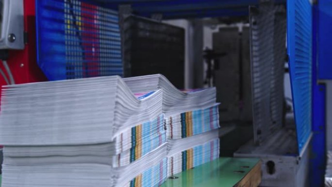 堆积如山的杂志从印刷设施内的机器里出来
