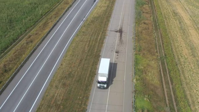 载货拖车在空旷的道路上行驶并运输货物的卡车的航拍。飞越送货卡车，沿着乡村的高速公路行驶。货物运输概念