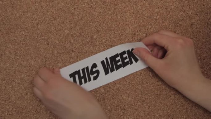 一位年轻的白人妇女将标题为 “本周” 的白皮书钉在软木板上，以更好地管理时间