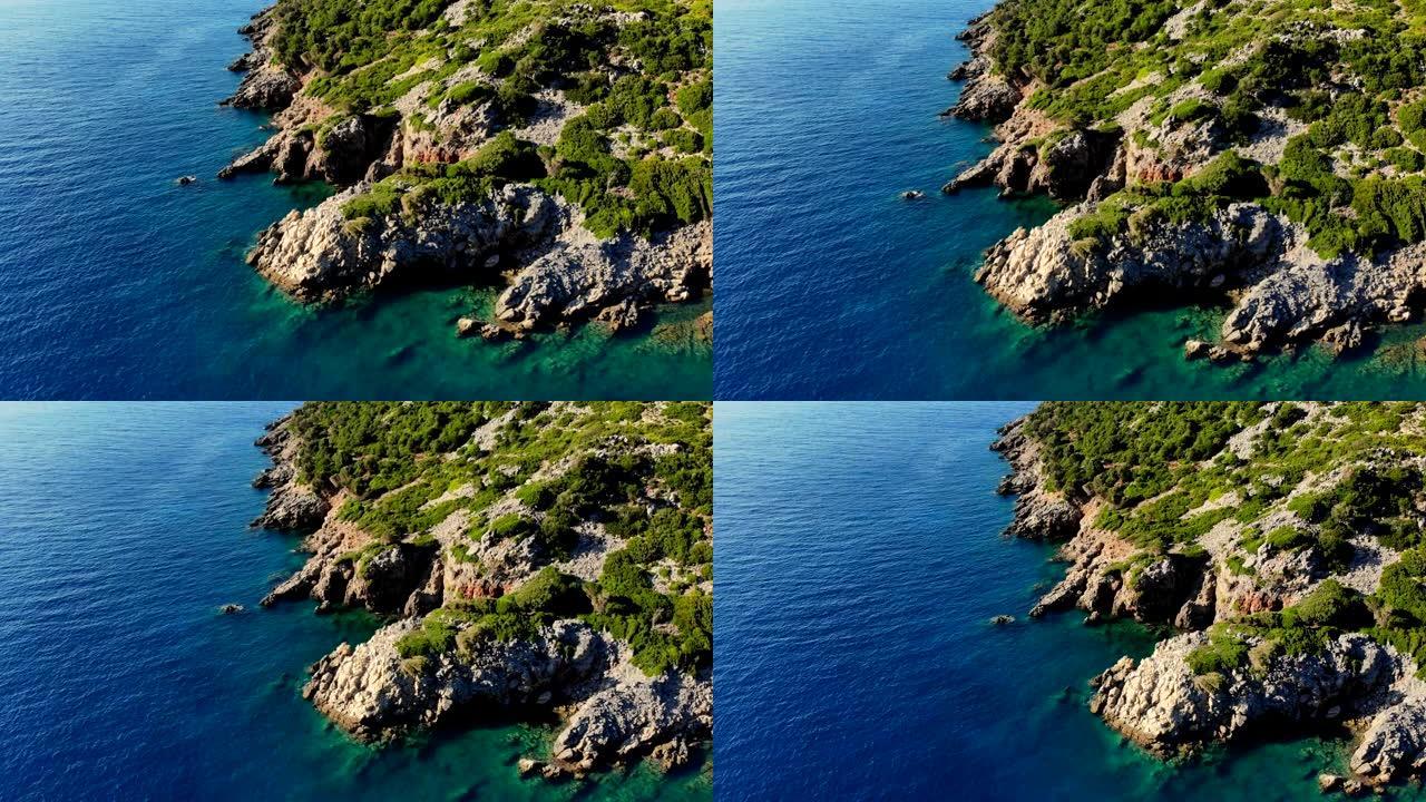 航空。从上方观看。美丽的夏日海景。希腊埃维亚岛的岩石海滩。大海碧绿，悬崖脚下的蓝色水，群山之间
