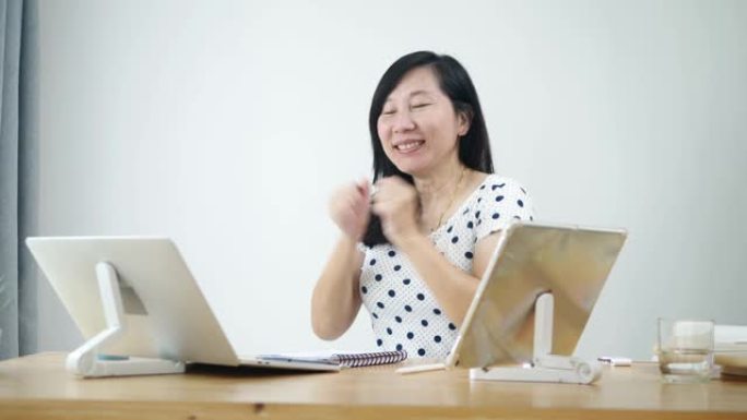 快乐的亚洲女人在新型冠状病毒肺炎期间在家工作时感到成功。