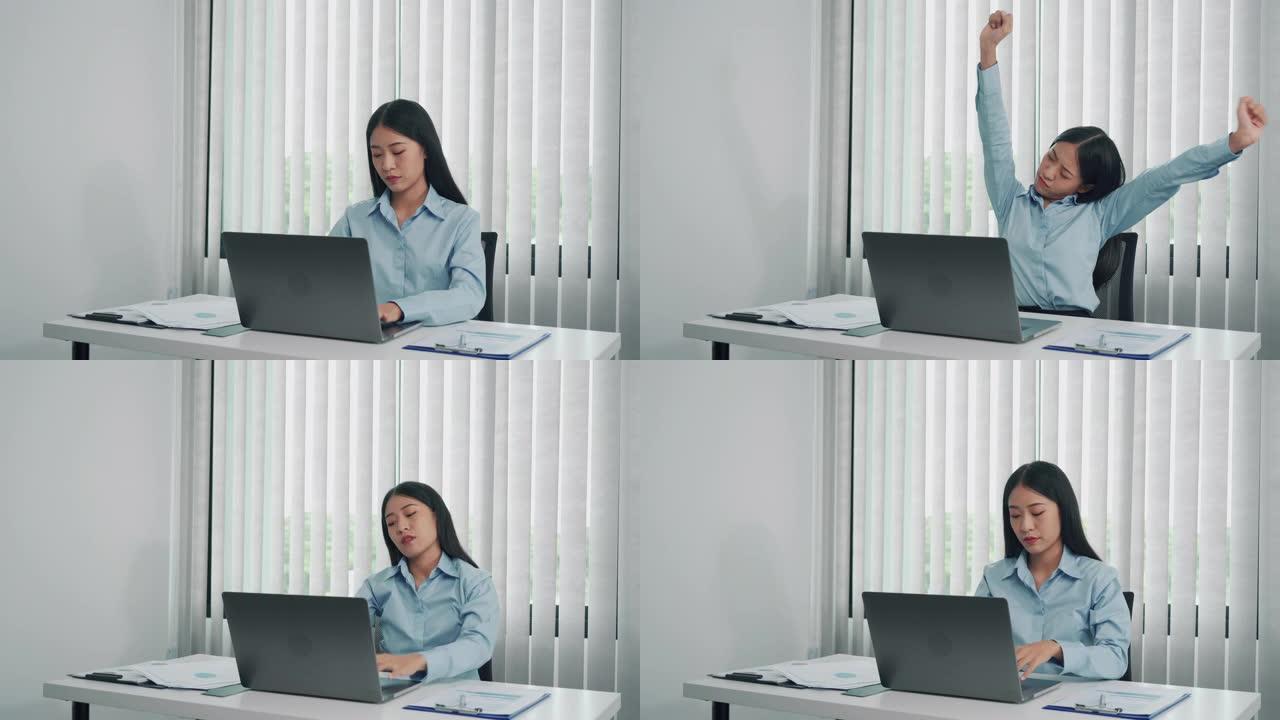 年轻的亚洲女性坐在办公室时伸展肌肉，以减轻压力。