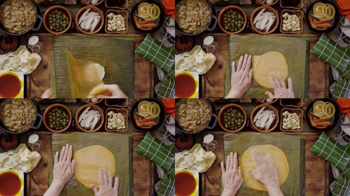 成熟的女人用手撒上玉米面团来制作委内瑞拉传统圣诞食品哈拉卡。实际搭配食材: 炖菜，杏仁，橄榄，洋葱，