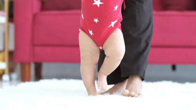 年轻的混血儿妈妈的特写抱着小婴儿学步在家学习走路，第一步走路是孩子的第一步主要步骤之一。母亲教婴儿在