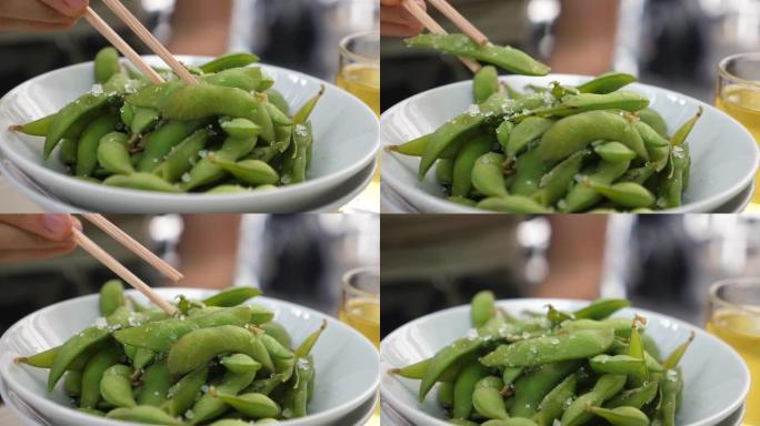 筷子从碗里摘毛豆。午餐的日本小吃。健康亚洲美食