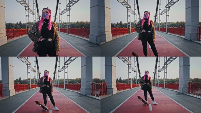 穿着非正式服装和防护面具的粉红色头发的时髦女士正站在滑板桥上摆姿势