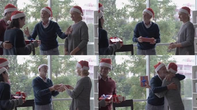 老人戴着红帽子，在圣诞节用餐时向家人赠送礼物或礼物