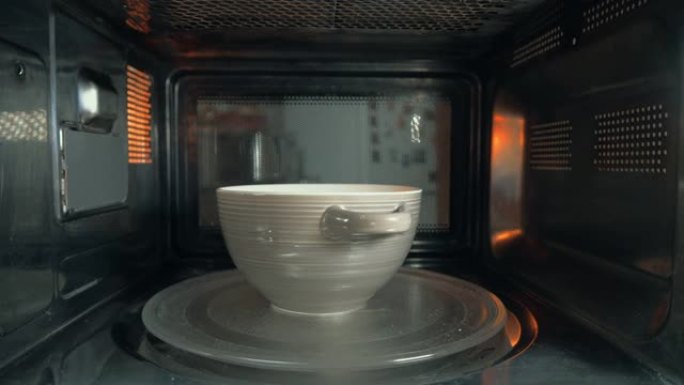 这个人把一碗食物放在微波炉里加热。摄像机内部。