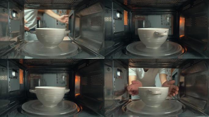 这个人把一碗食物放在微波炉里加热。摄像机内部。