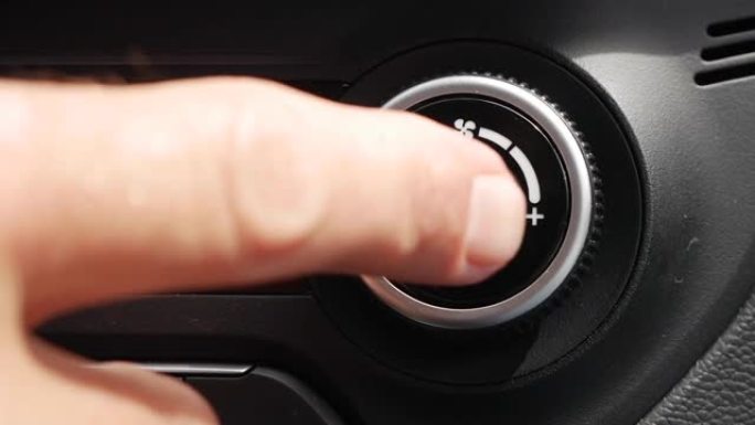 按下按钮关闭汽车空调的特写镜头。男人的手转动按钮