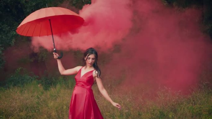 穿着红色连衣裙的美女，手里拿着雨伞。创意烟雾弹。