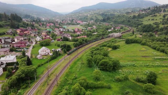 货运列车在森林喀尔巴阡山脉通过铁路运送电力机车。空中摄影无人机在夏天的视野。