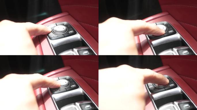按下车内后视镜调节按钮的手指特写。