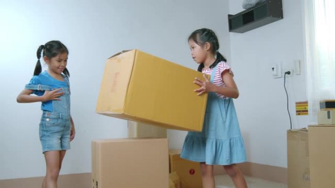 两名亚洲女童帮助父母在搬家日搬迁前准备箱子里的东西。房屋翻新和搬迁概念。慢动作镜头。