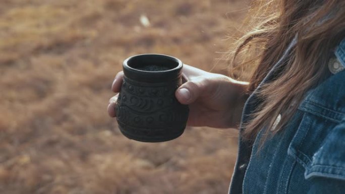 关闭妇女站在户外并拿着一杯热茶的镜头。