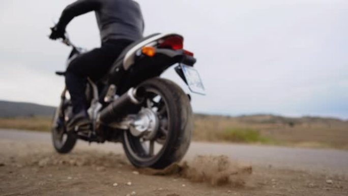 骑自行车的人在尘土飞扬的道路上驾驶摩托车