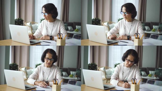 成熟的女性会计使用笔记本电脑，在家庭办公室的餐桌上写作