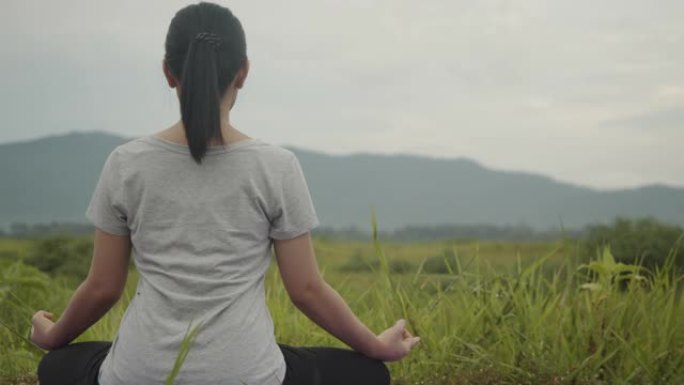 年轻的亚洲妇女做瑜伽练习冥想，在日出时在山上表演精神瑜伽姿势。