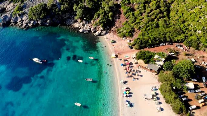 航空。顶视图。美丽的夏日海景。希腊埃维亚岛的野生海滩。绿松石色的海湾，山脚下的蓝色海水。度假者在海滩