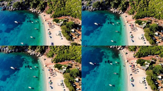 航空。顶视图。美丽的夏日海景。希腊埃维亚岛的野生海滩。绿松石色的海湾，山脚下的蓝色海水。度假者在海滩