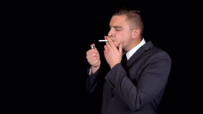 这位年轻的商人不能点燃香烟，决定戒烟。黑色背景上穿着黑色西装的男人
