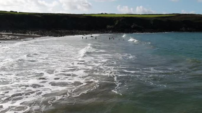 一架无人驾驶飞机扫过海岸线，发现一群女游泳者跳入海浪滚滚到海滩上。