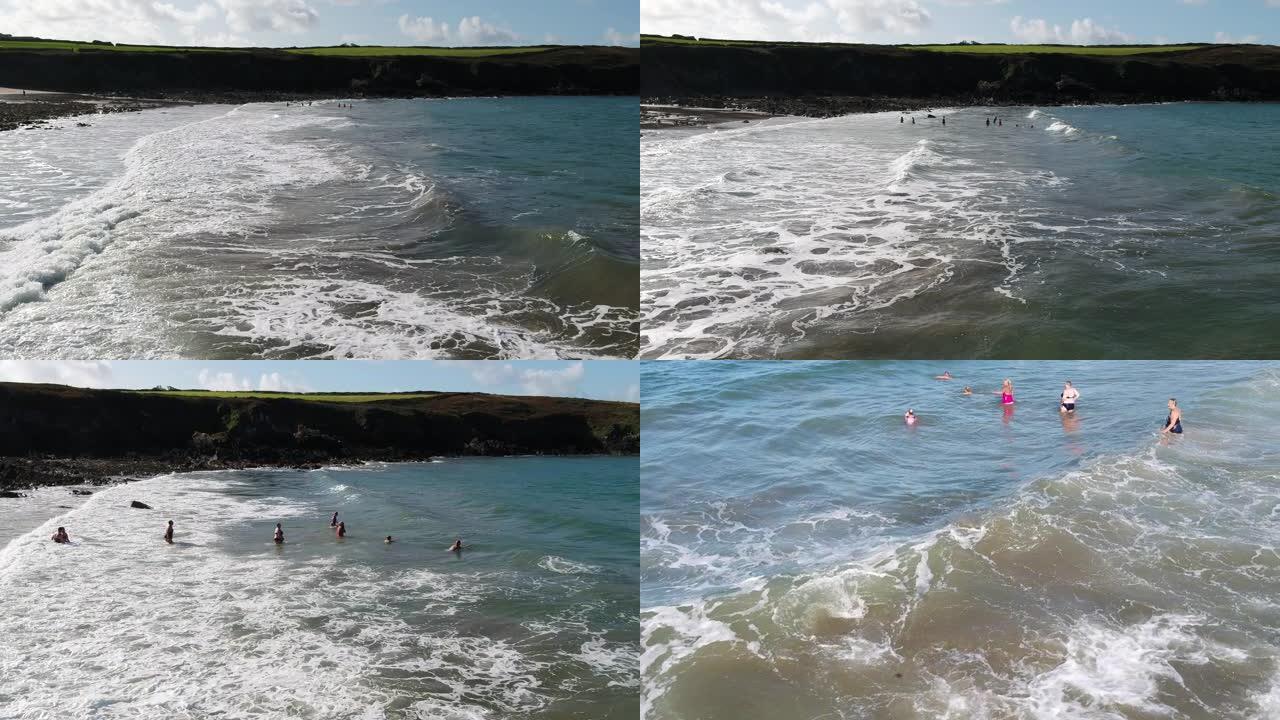 一架无人驾驶飞机扫过海岸线，发现一群女游泳者跳入海浪滚滚到海滩上。