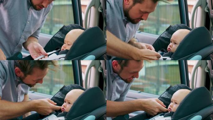 车内摄像头。特写男婴坐在车内的婴儿汽车座椅上。年轻的大胡子父亲系好安全带，抚摸脸颊，然后关上门。慢动