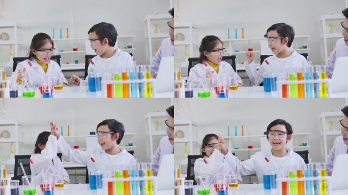 小学科学教室: 亚洲儿童在科学家制服学习科学实验室实验管玻璃水桌上各种颜色。