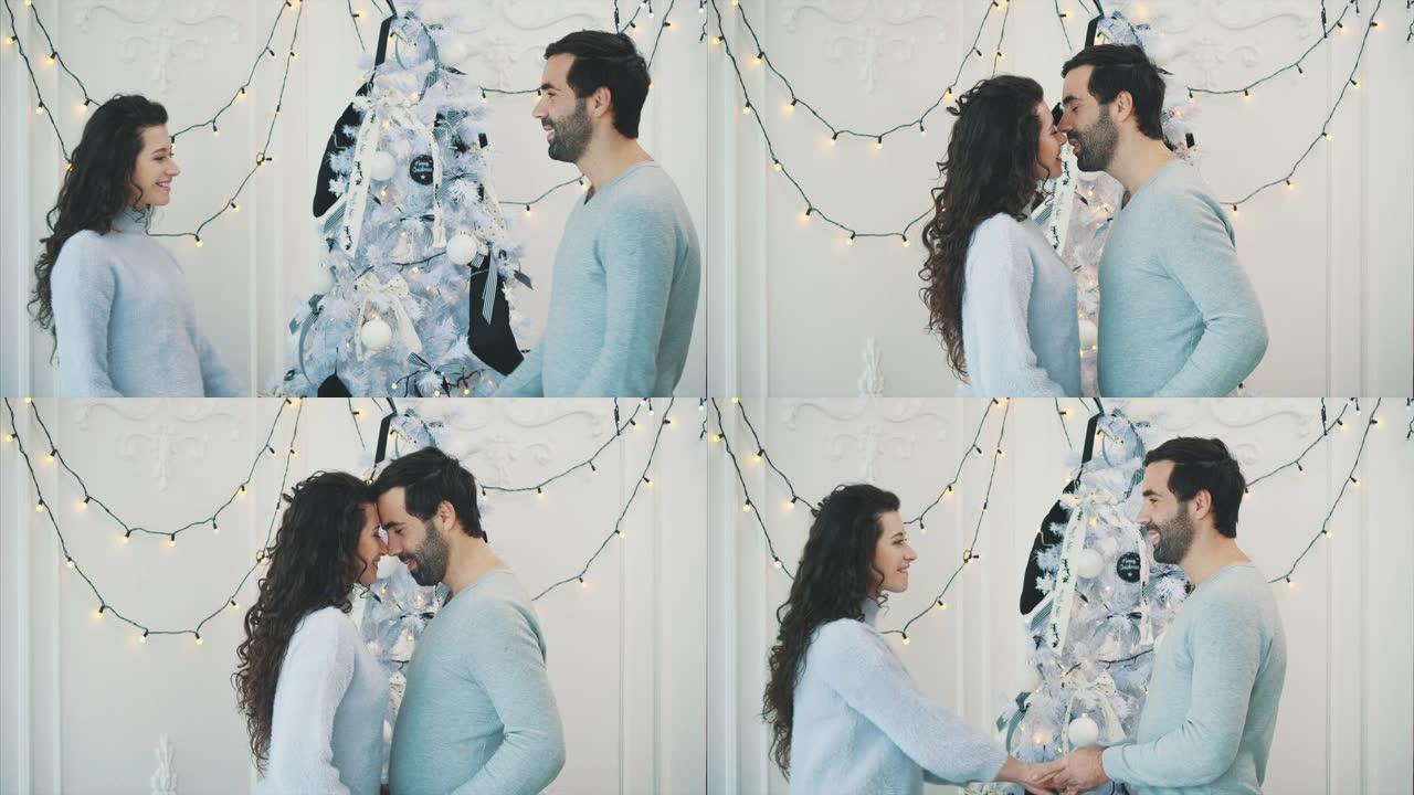 一对恩爱的夫妇在新年前夜在圣诞树附近相遇，亲吻，抚摸额头并互相牵着手。