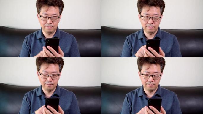 亚洲中年男性试图在手机上阅读一些东西。