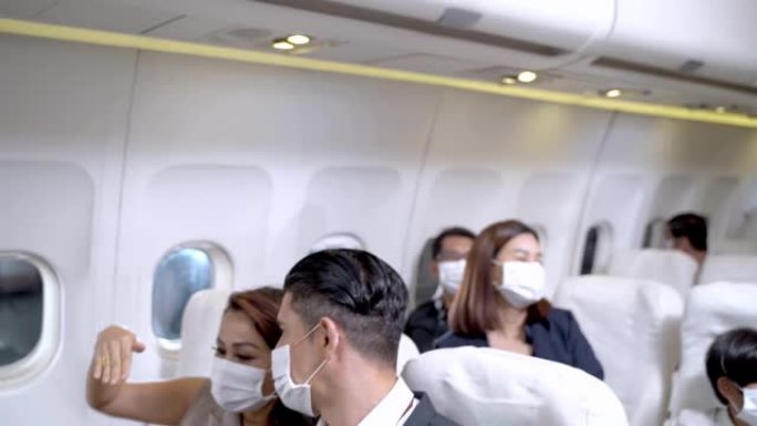 商人和戴着口罩的女人说话，坐在飞机座位上。健康保障航空旅行运输的概念新常态。