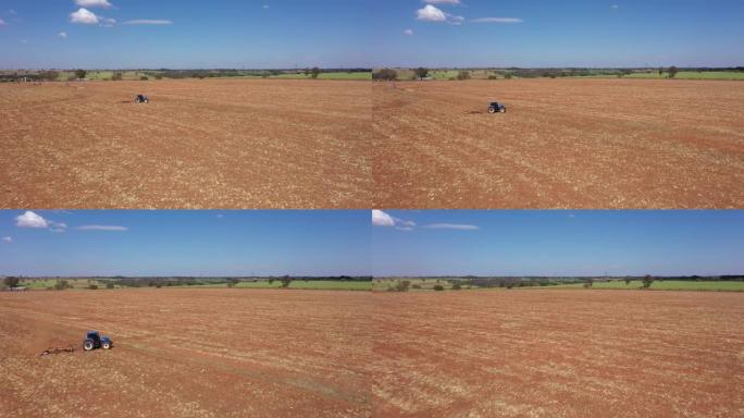 拖拉机耕地-蓝色拖拉机在土地上耕作的空中视频-蓝色拖拉机耕作和准备红色土地