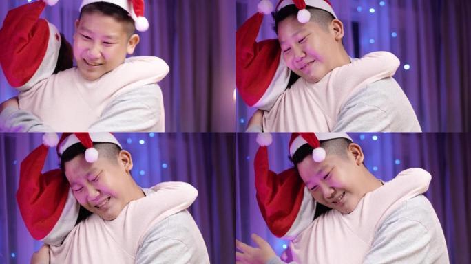 亚洲兄弟在家里的圣诞晚会上拥抱他的妹妹，爱和情感的概念。