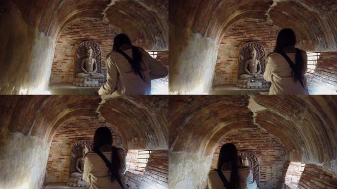 年轻女子在老庙和佛头雕像旅行