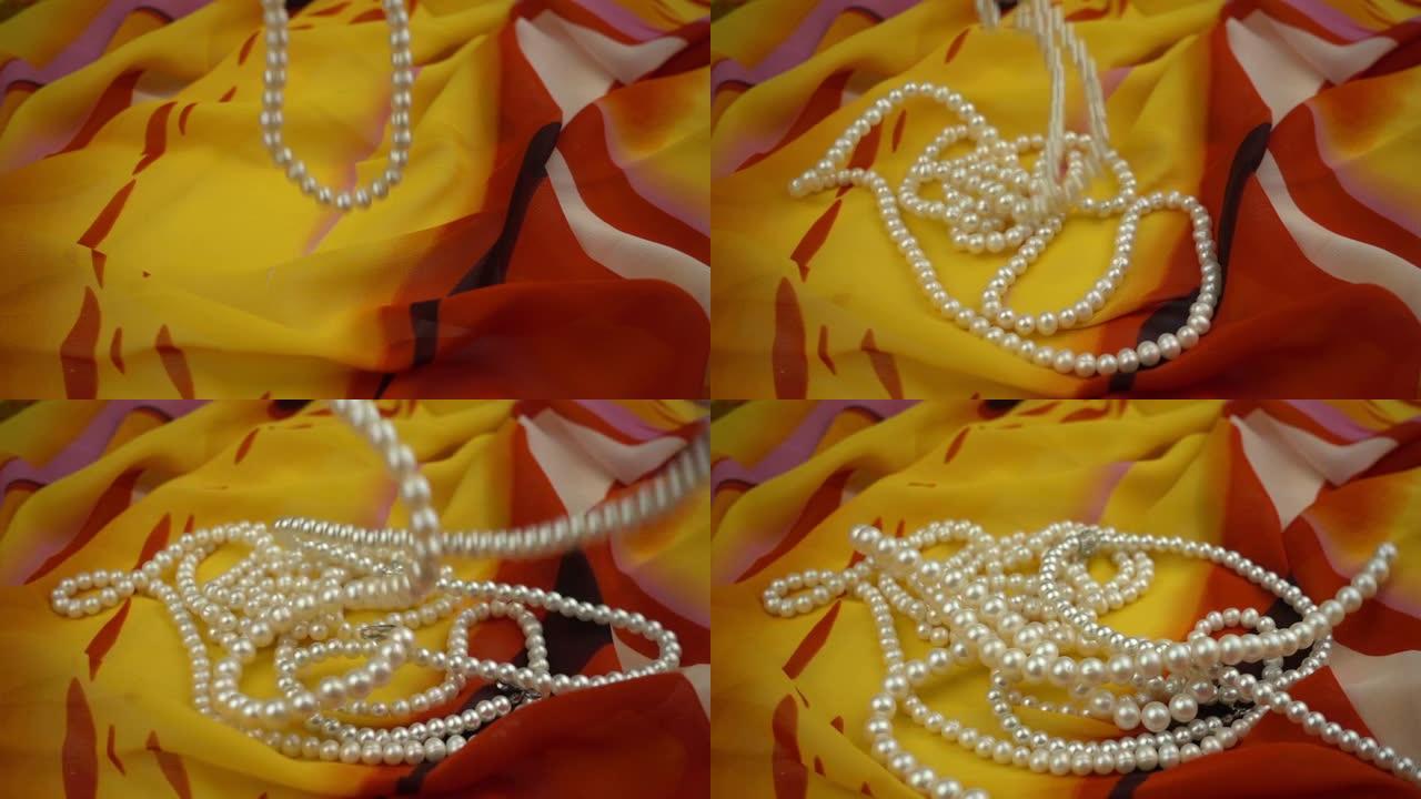 慢动作在时尚的多色柔软织物上落下珍珠首饰。