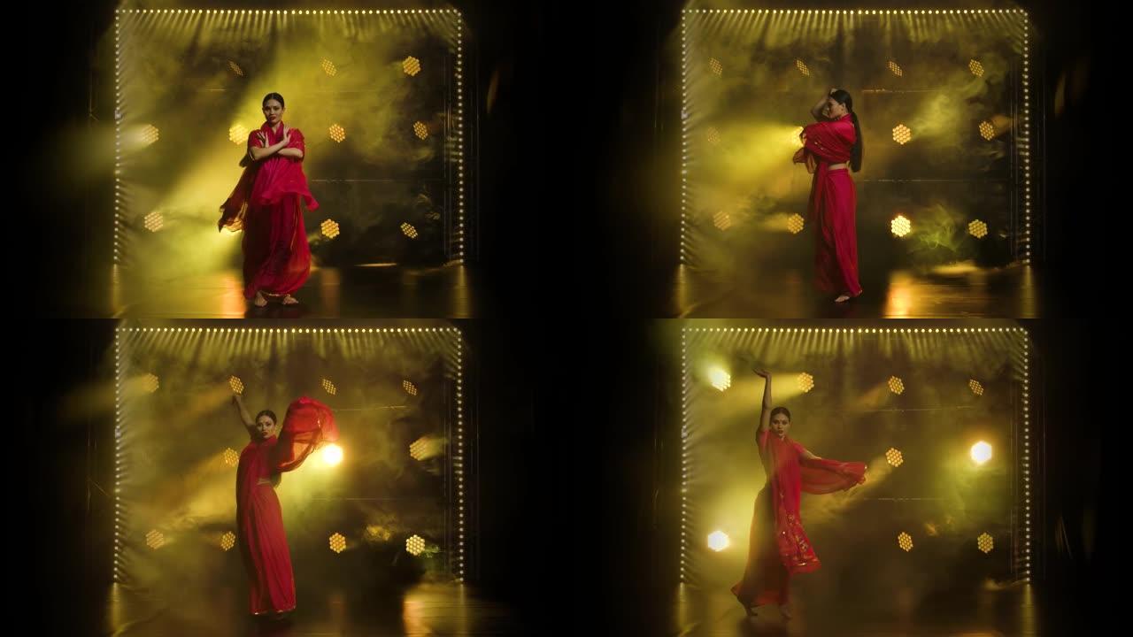 穿着红色纱丽的年轻女孩舞者。印度民间舞蹈。在黑暗的工作室里拍摄，有烟雾和黄色霓虹灯。慢动作
