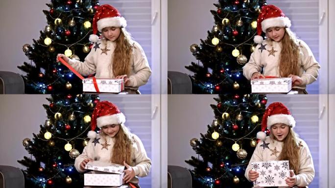 小高加索女孩坐在圣诞树附近，用一些特别的东西打开她的礼物。假期和庆祝活动