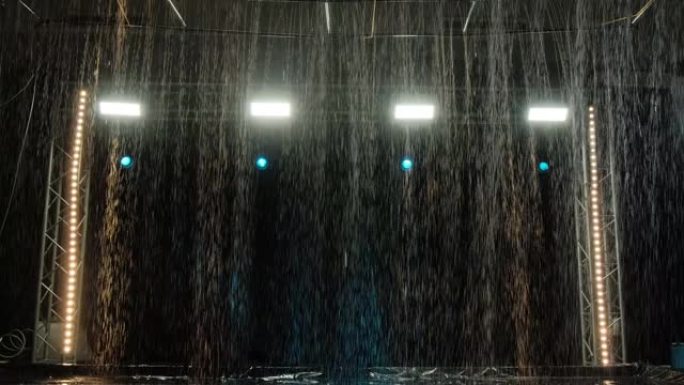 在聚光灯的背景下，水上工作室里下雨的效果。水质地。慢动作